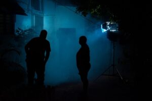 Zwei Silhouetten stehen nachts im blauen Licht einer Filmszene